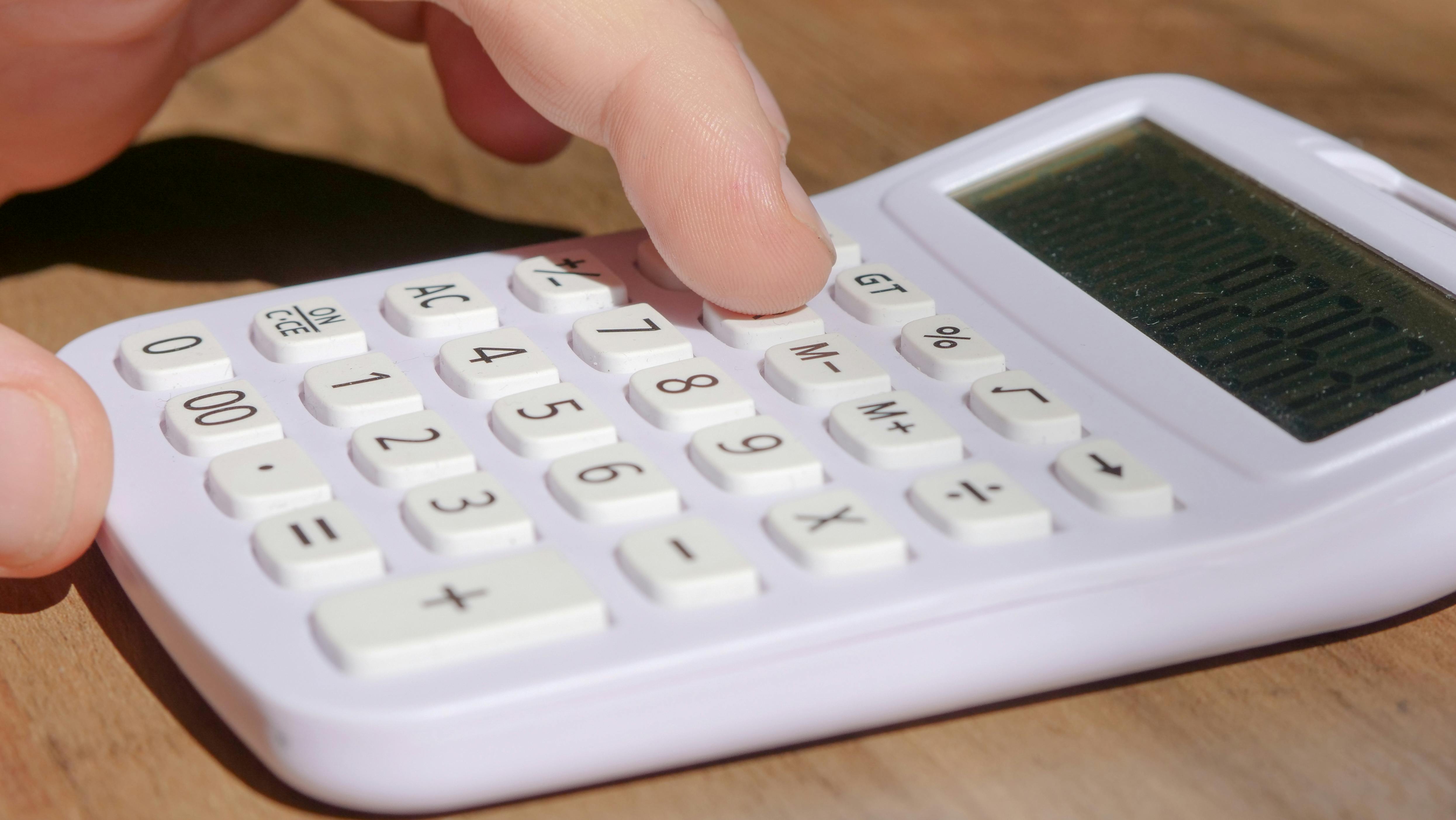 someone pressing buttons on a white calculator