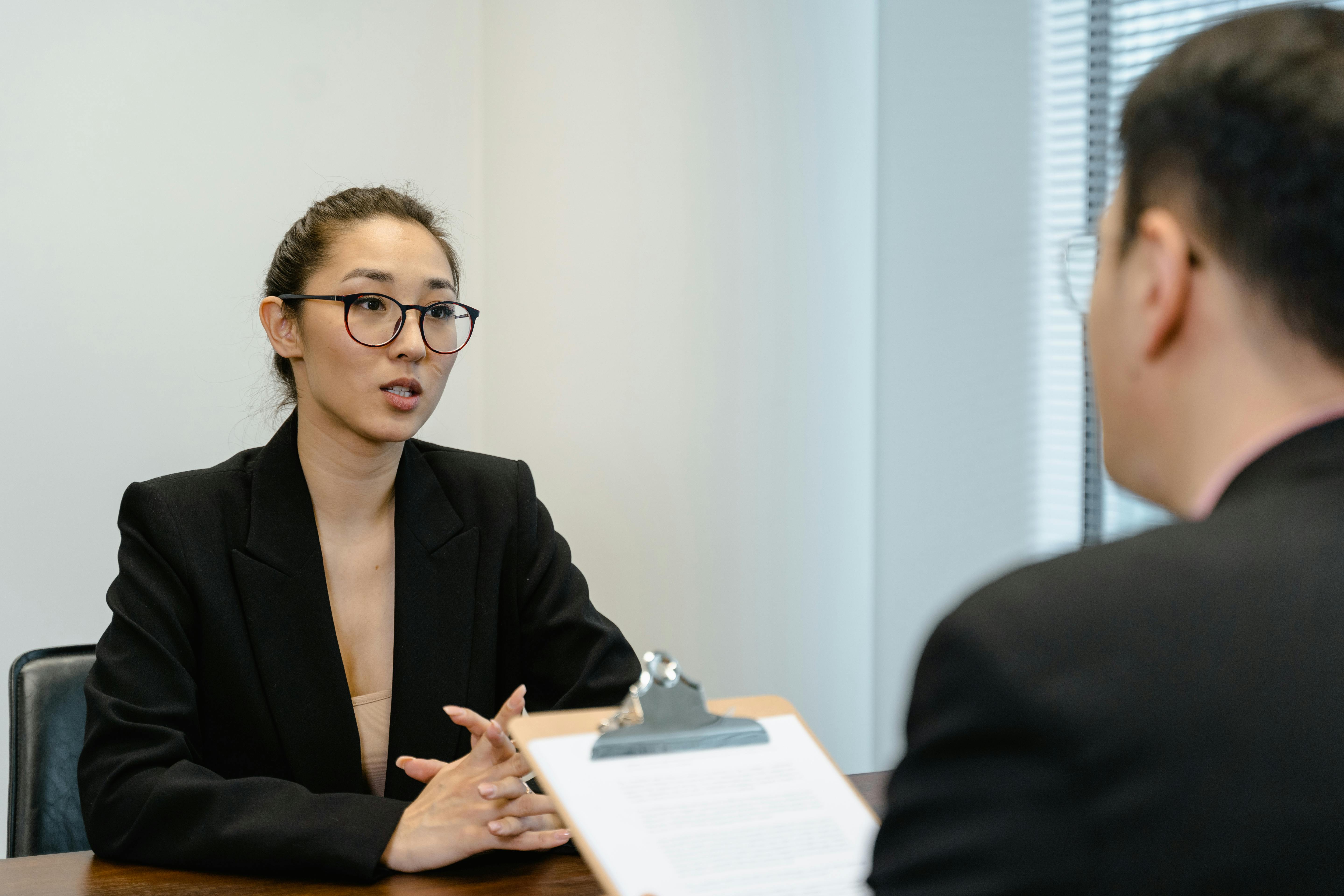 two people in suits having a conversation while one holds a clipboard