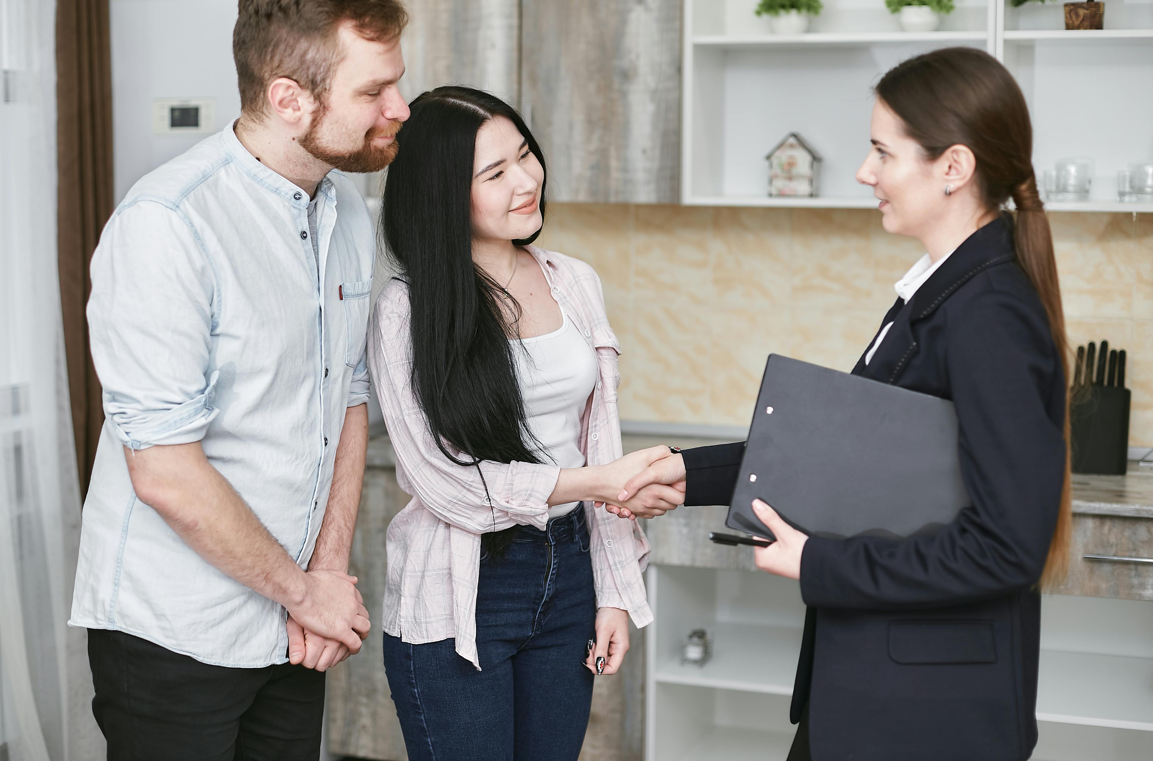 a couple shaking hands with a woman in a suit